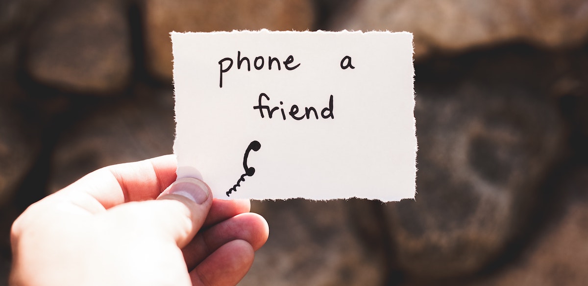 a hand holding a note that says: "Phone a friend."