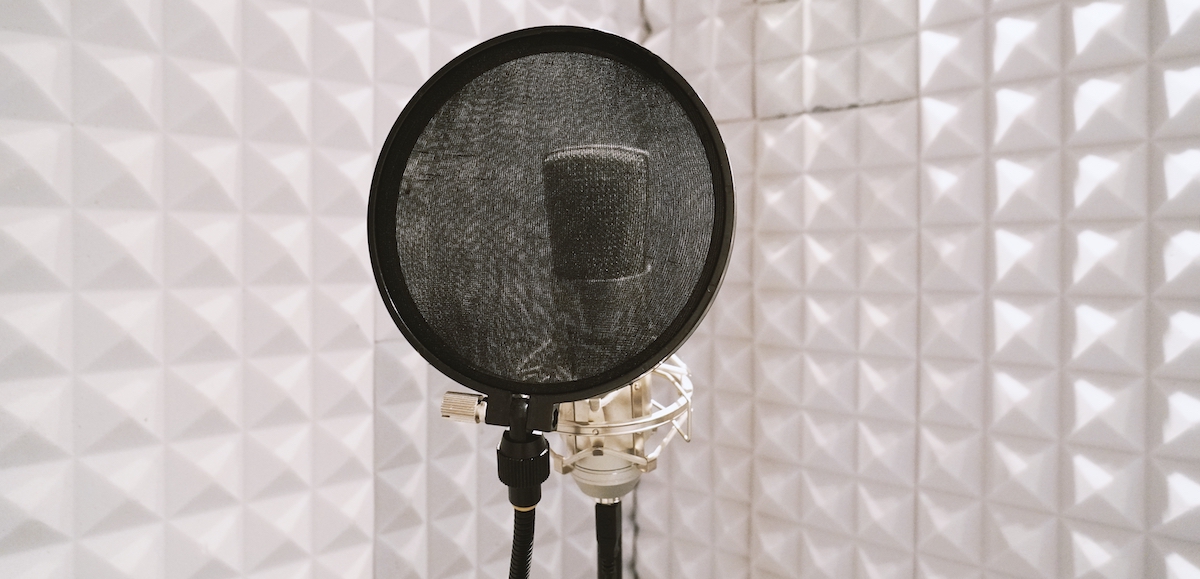 5 must-haves for a voice actor's recording environment: image of a microphone and pop filter in a soundproofed room.