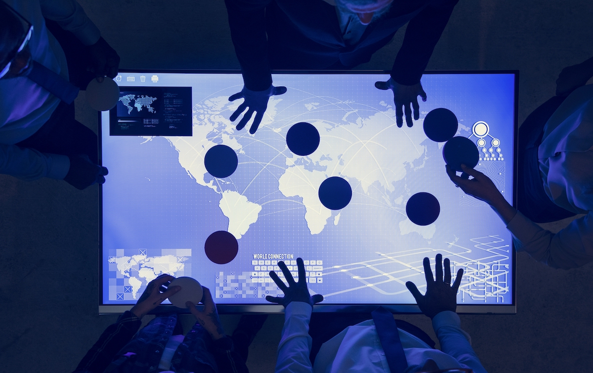 Video marketing strategy: image of people with their hands on a screen showing a global map