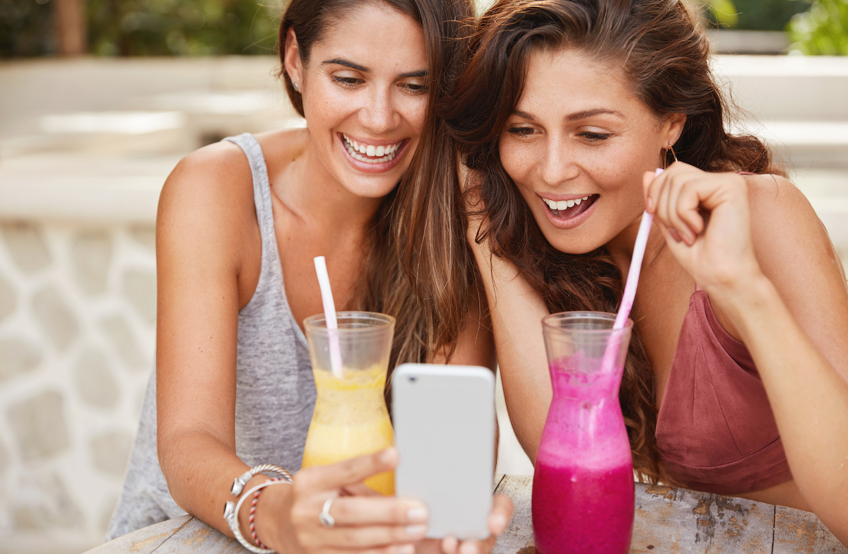 Humor in ads: image of two young women laughing at funny videos on a smartphone